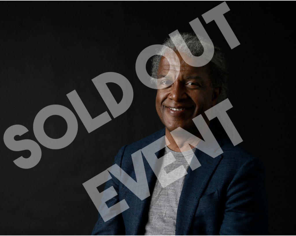 Portrait image of Elvis Mitchell, solid black backdrop with African American man in center and words sold out overlaid on image.